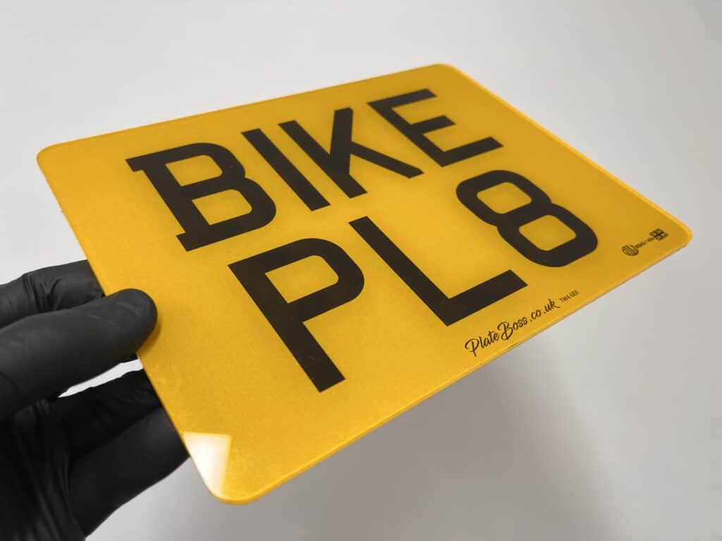 A 9 x 7 inch road-legal motorbike number plate held in the workshop