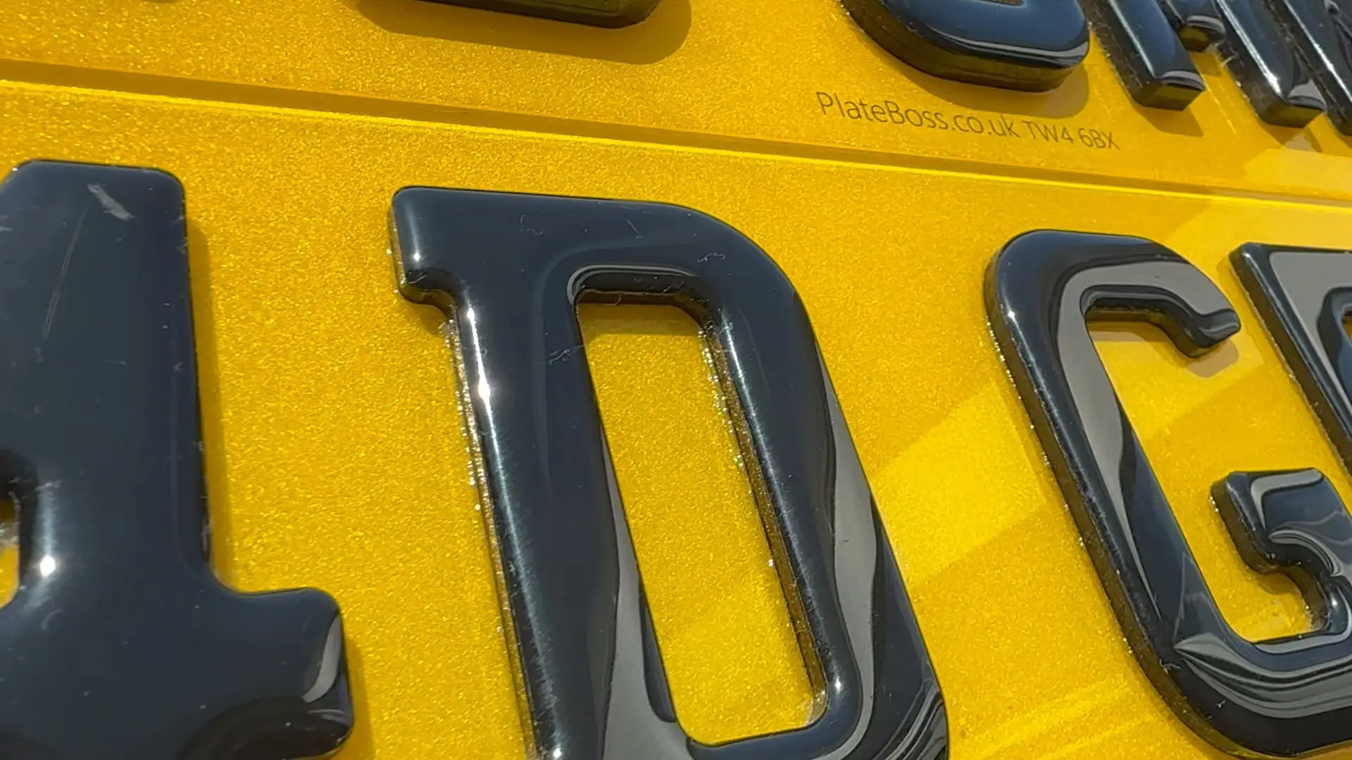 Close-up of raised 4D gel characters on a yellow rear number plate, made at PlateBoss