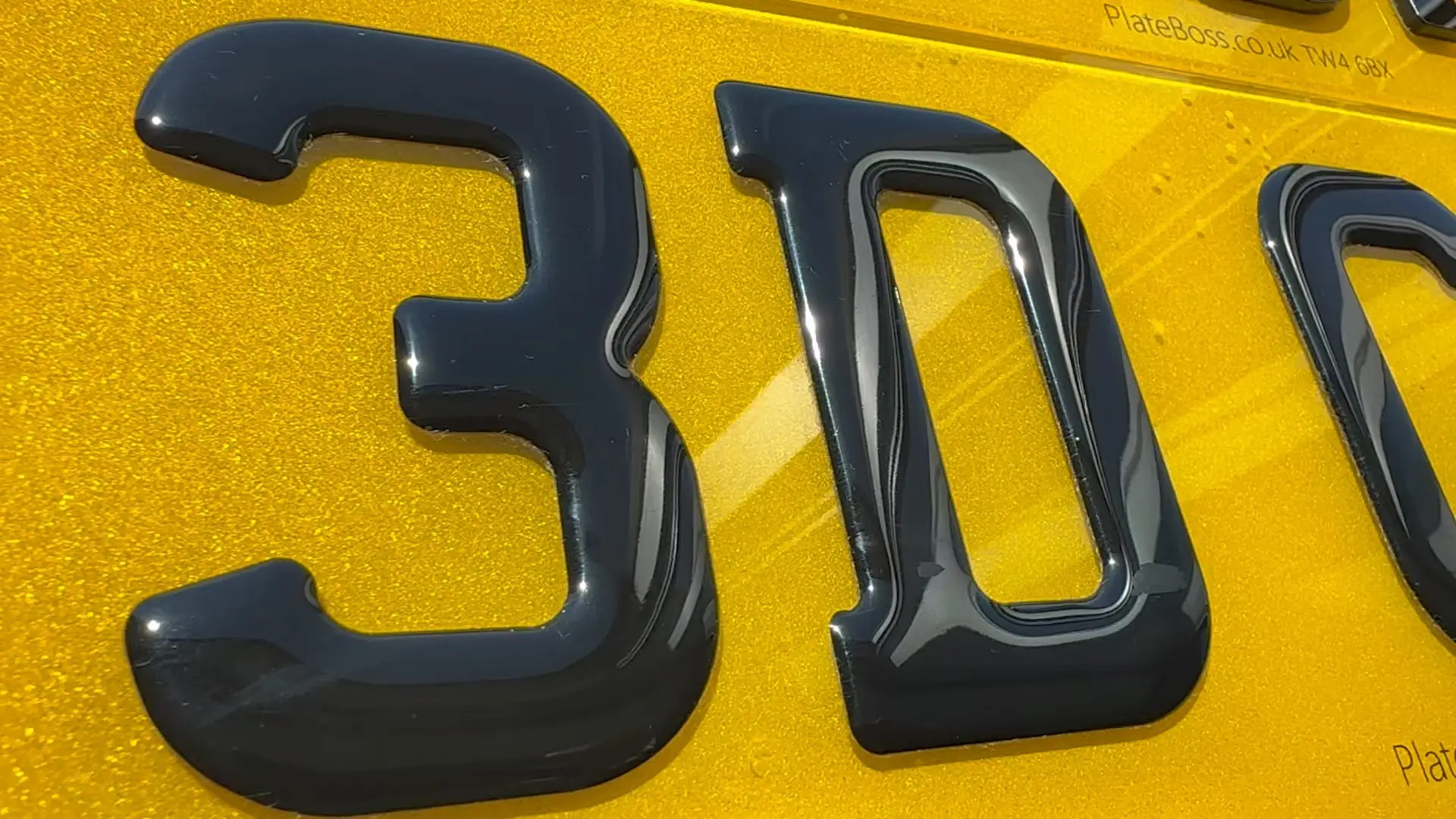 Close-up of raised 3D gel characters on a yellow rear number plate, made at PlateBoss