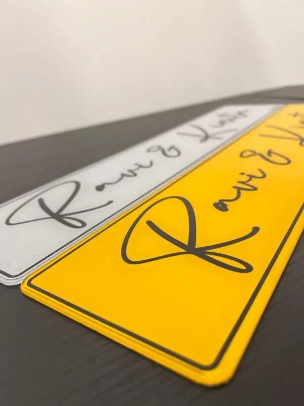 Personalised wedding car number plate with the couple's names handwritten on a yellow plate